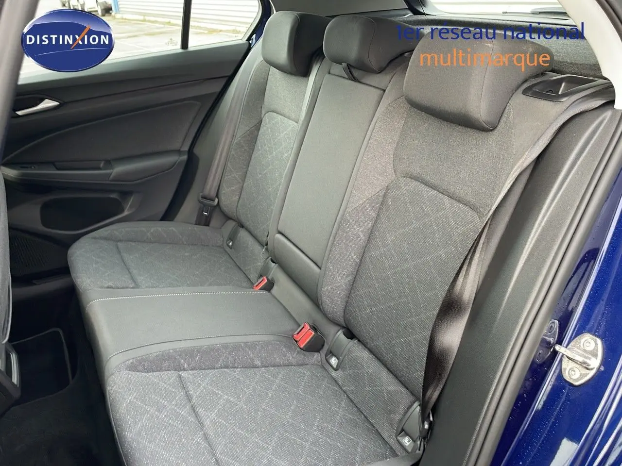 Vue intérieure sur les sièges arrière en tissu gris de la Volkswagen Golf VIII bleu lapiz metal avec ceinture de sécurité.