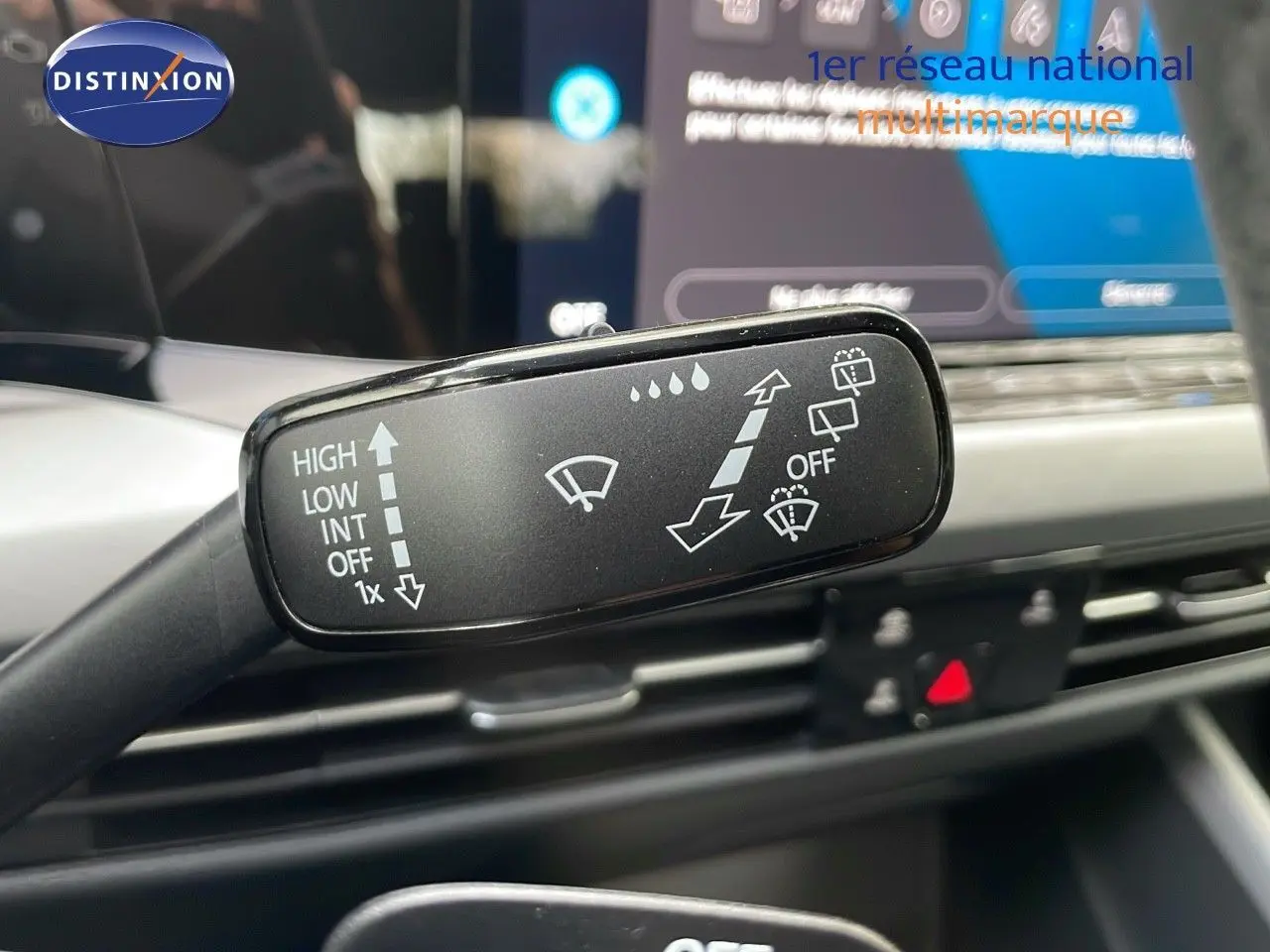 Gros plan sur la commande d'essuie-glace de la Volkswagen Golf VIII bleu lapiz metal, intérieur moderne et écran tactile visible.