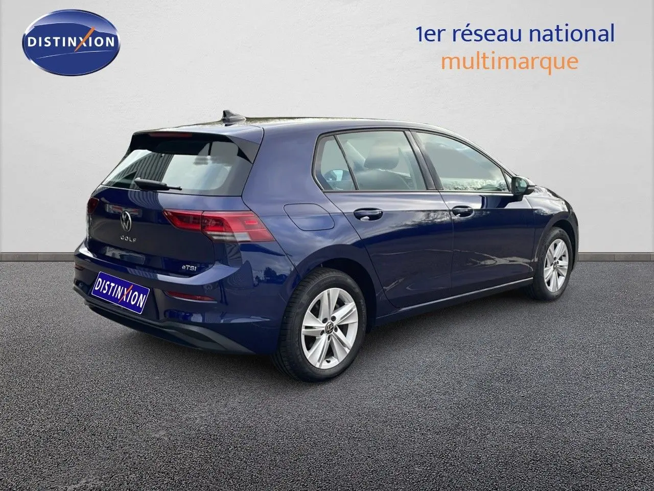 Vue 3/4 arrière droite d'une Volkswagen Golf VIII bleu lapiz metal, avec jantes alliage et cinq portes visibles.