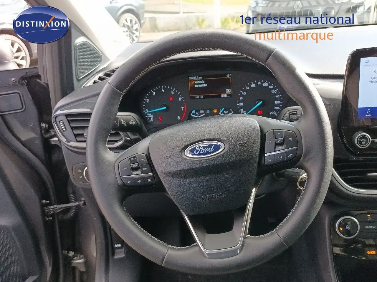 Vue intérieure centrée sur le volant Ford Puma gris foncé, tableau de bord et écran tactile visibles côté conducteur.