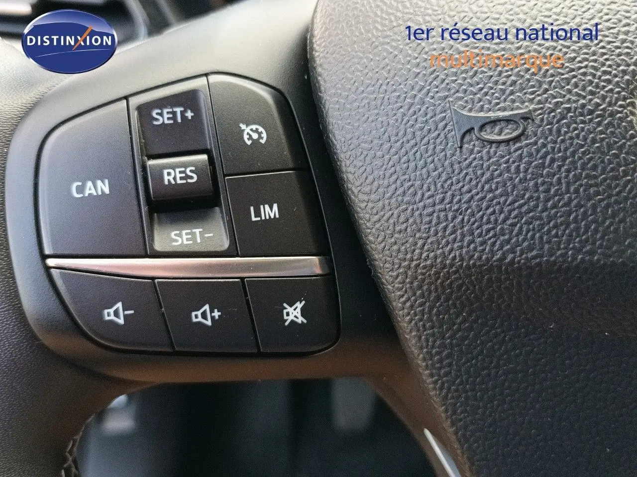 Gros plan sur les commandes de régulateur de vitesse et volume audio au volant noir du Ford Puma gris foncé 2023.