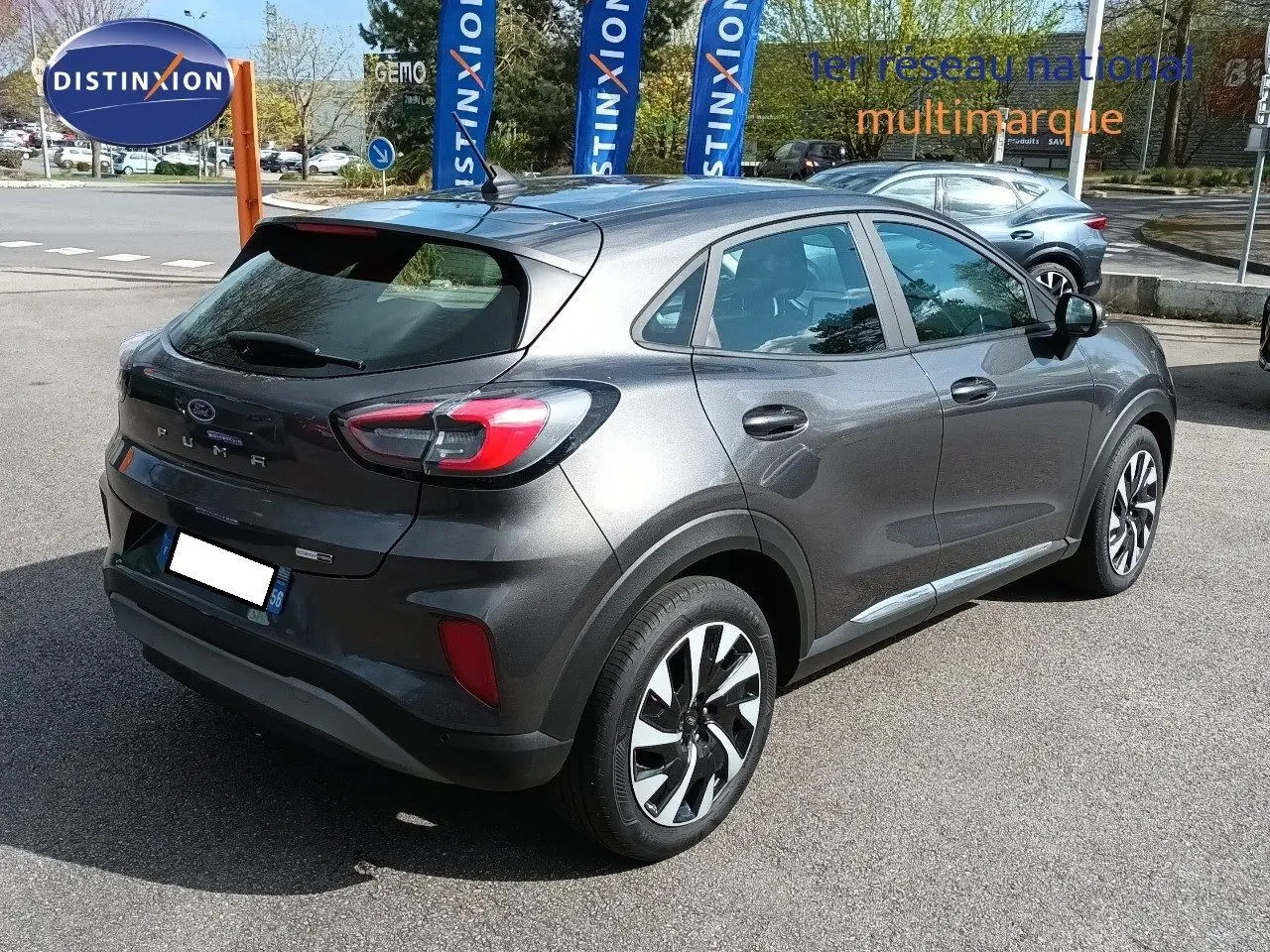 Vue 3/4 arrière droite d'un Ford Puma gris foncé métal 2023 avec jantes alliage et feux arrière LED distinctifs.