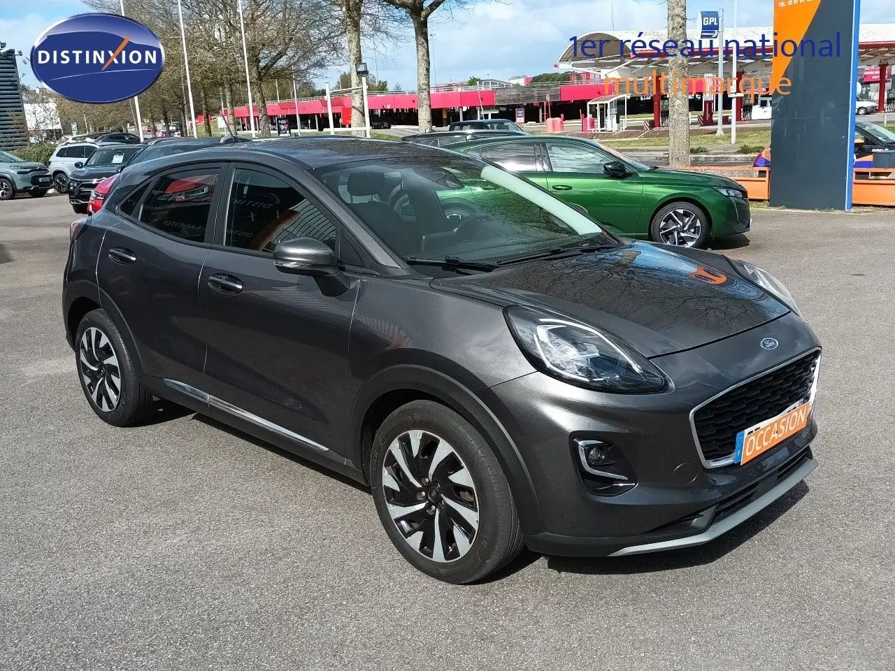 Ford Puma gris foncé métal vue 3/4 avant droit, avec calandre noire et jantes bicolores distinctives.