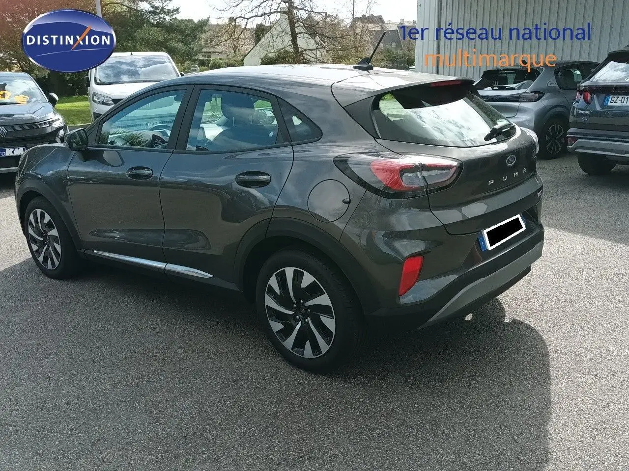 Ford Puma gris foncé métal vu en 3/4 arrière droit, mettant en valeur ses feux arrière et ses jantes bicolores.