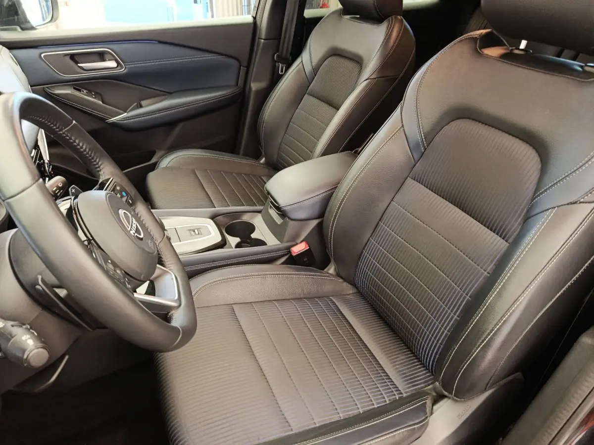 Vue intérieure côté conducteur du Nissan Qashqai 2023, sièges en cuir noir et volant multifonctions.