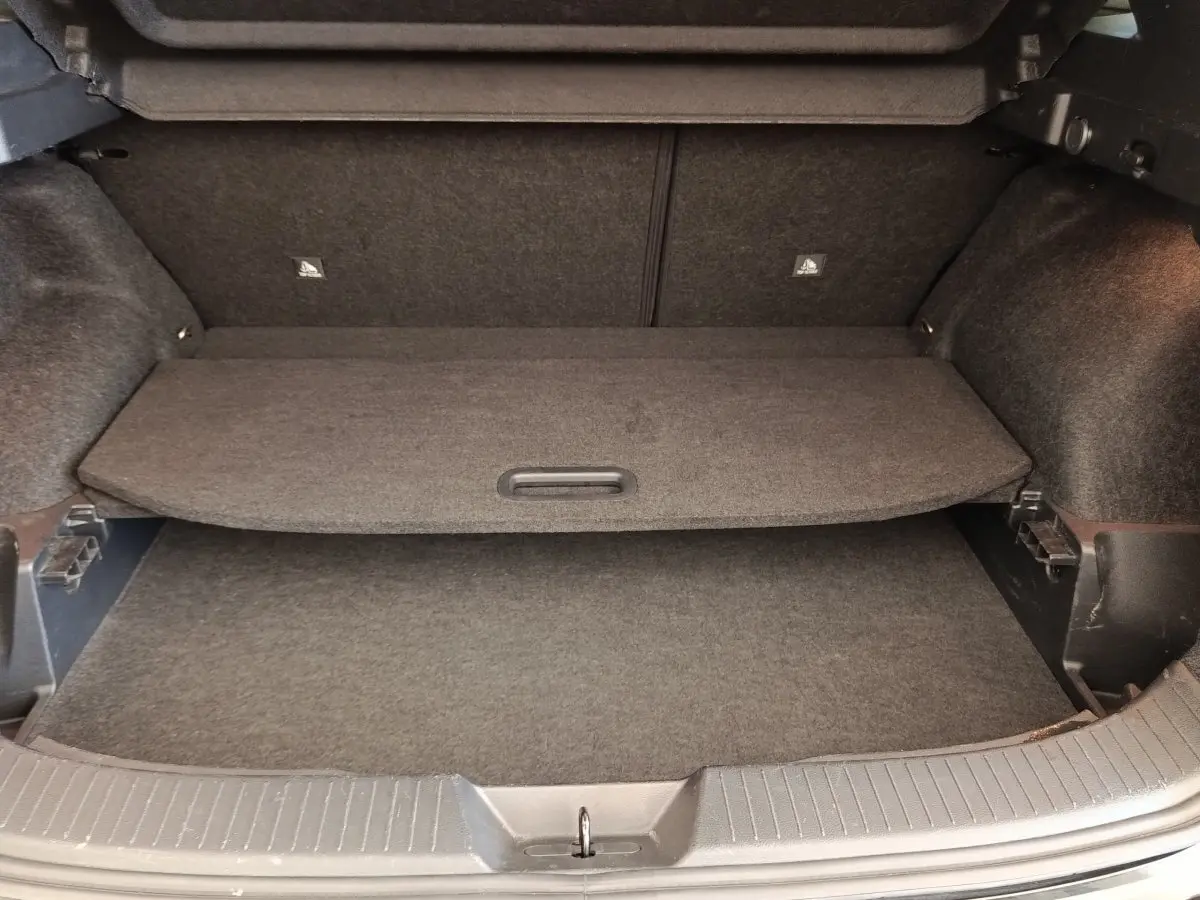 Coffre ouvert du Nissan Qashqai noir 2023, vue de l'intérieur montrant la tablette de séparation et le revêtement gris.