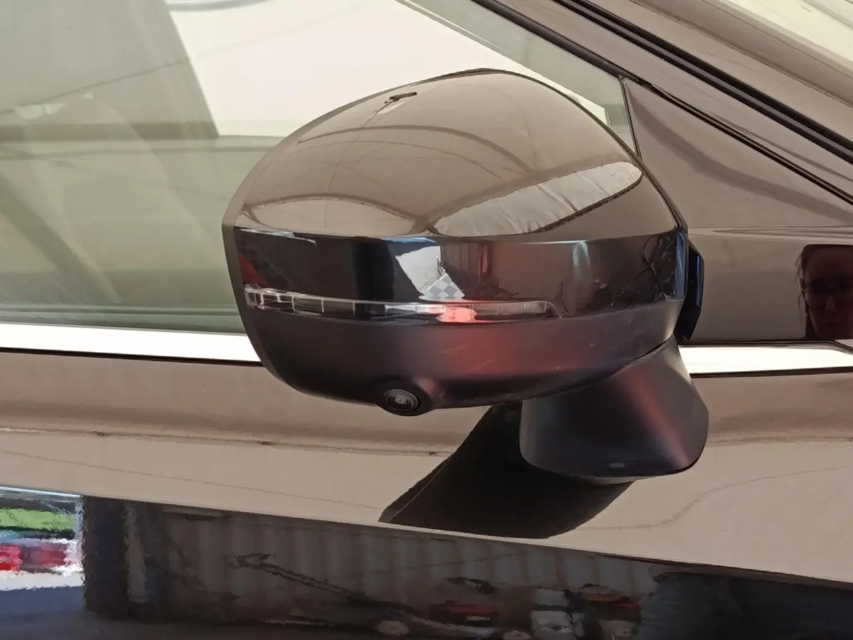 Rétroviseur côté gauche noir brillant du Nissan Qashqai 2023 avec clignotant intégré et caméra de surveillance.