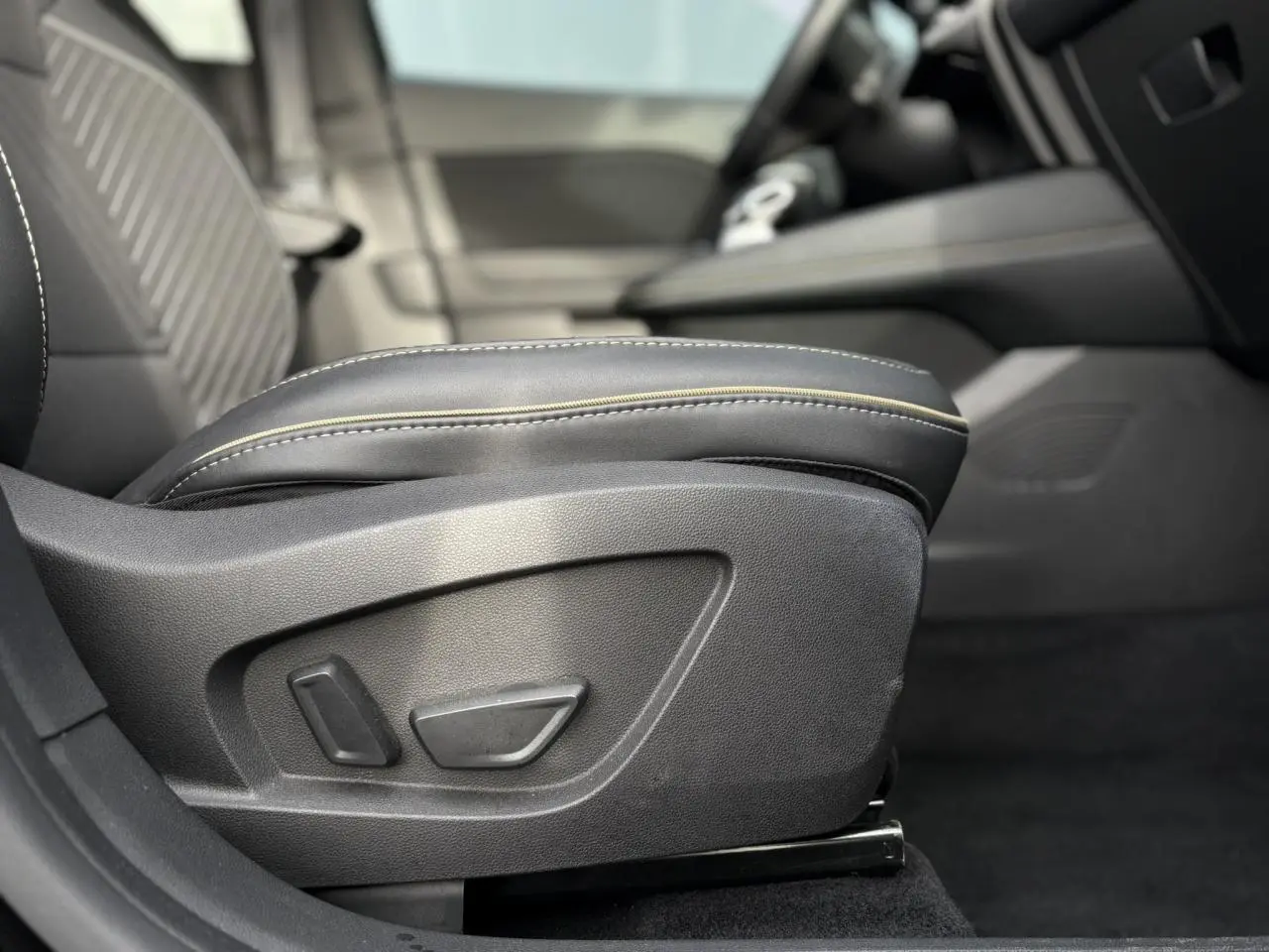 Détail de l'accoudoir noir avec surpiqûres beiges côté conducteur de la Renault Symbioz E-Tech Full Hybrid 2025.