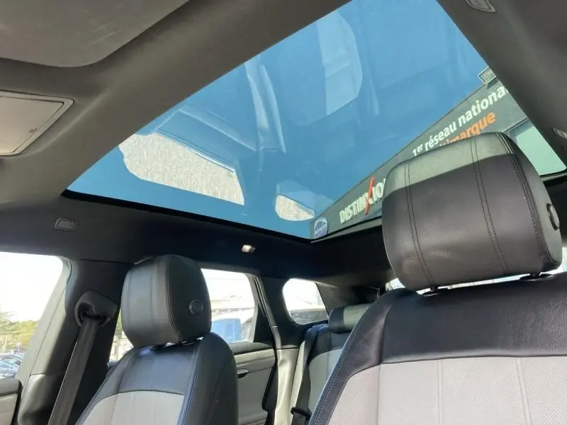 Intérieur du Range Rover Evoque 2019 avec toit panoramique, sièges cuir bicolores et ambiance lumineuse naturelle.