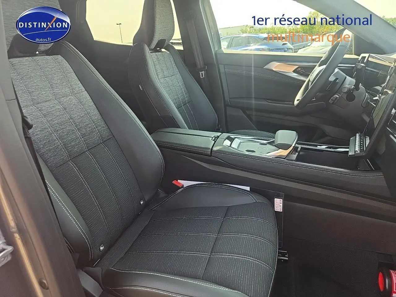 Vue intérieure côté conducteur du Renault Austral 2025 avec sièges tissu noir et accoudoir central cuir.