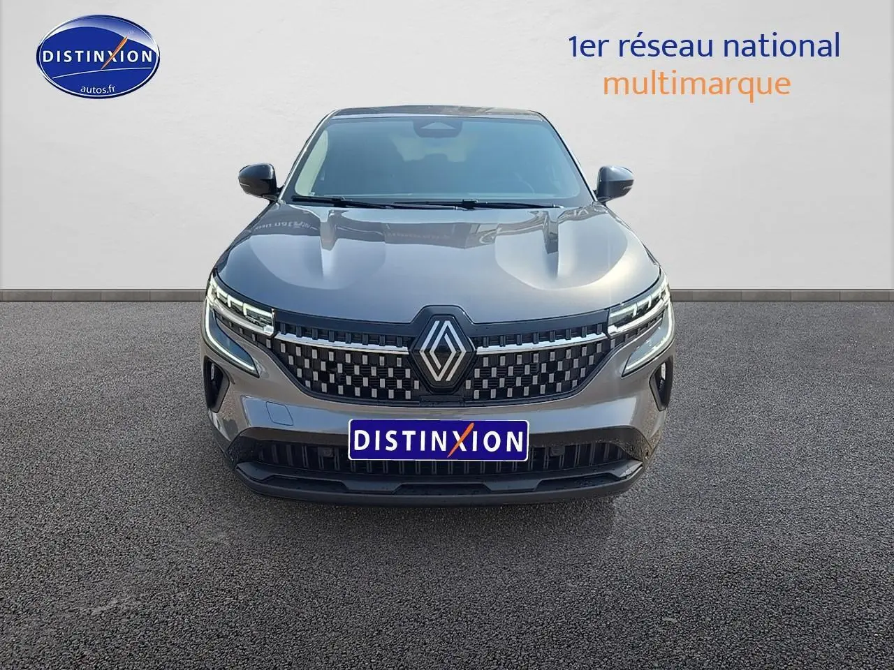 Renault Austral gris schiste vu de face, avec calandre moderne et phares LED distinctifs allumés.