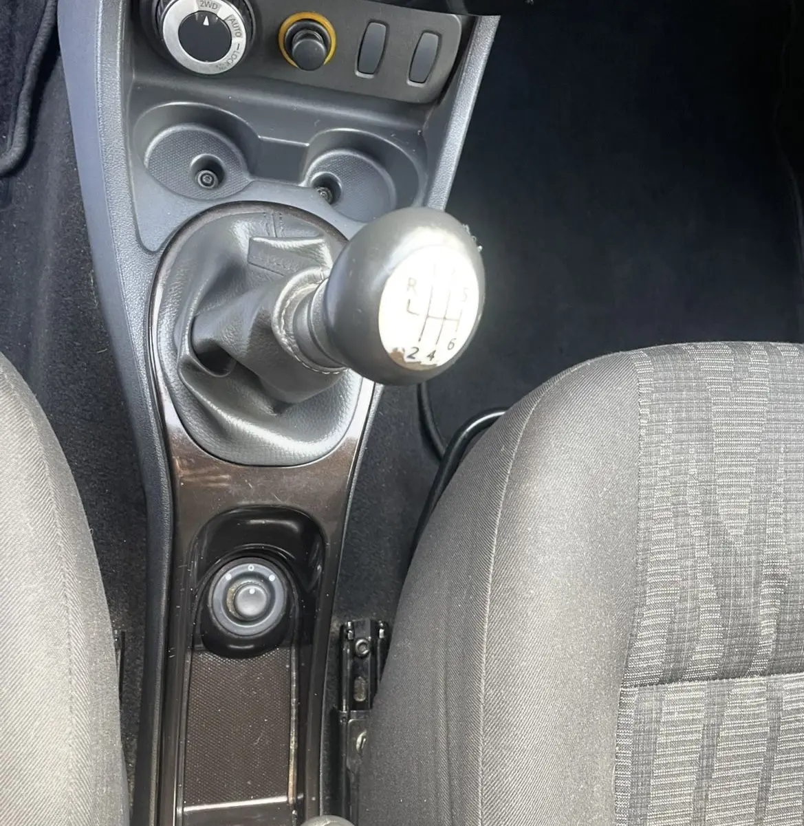 Vue rapprochée de la console centrale du Dacia Duster 2011, montrant levier de vitesses manuel et sièges gris.