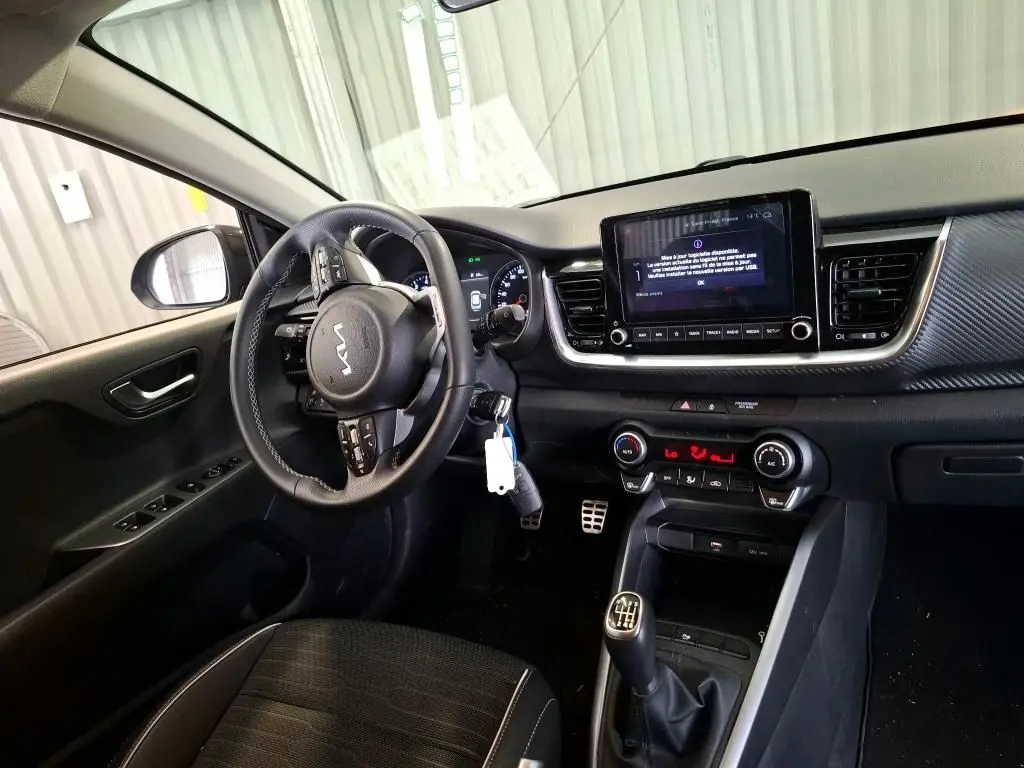 Intérieur du Kia Stonic 2024 gris météore, vue côté conducteur, volant multifonction et boîte manuelle visible.