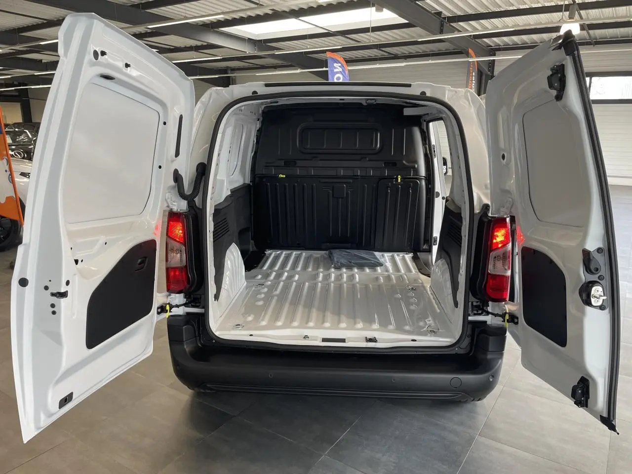 Vue arrière du Peugeot Partner blanc 2026 avec portes battantes ouvertes et compartiment de chargement vide.