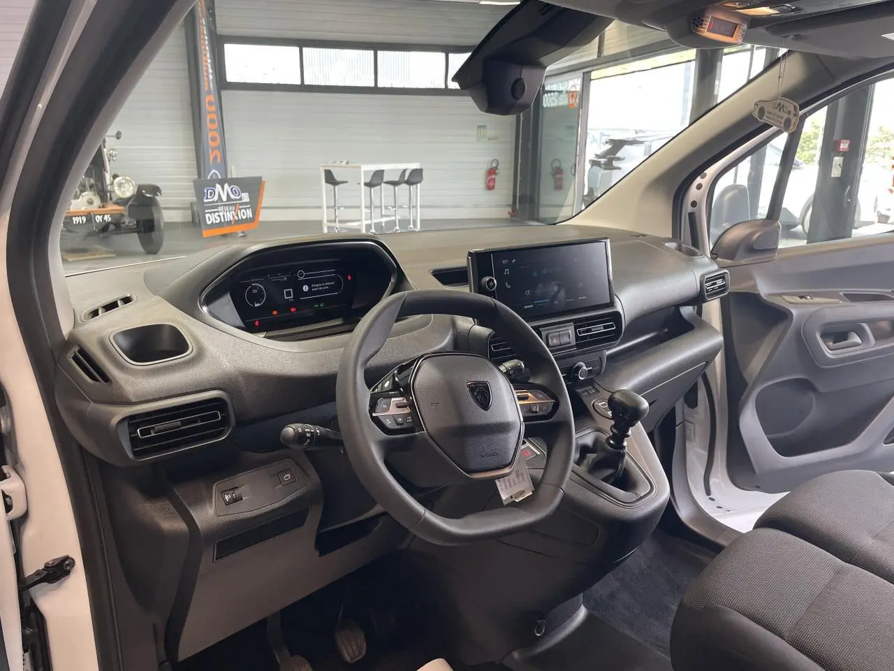 Vue intérieure côté conducteur du Peugeot Partner blanc 2026, tableau de bord moderne avec écran tactile et volant multifonctions.