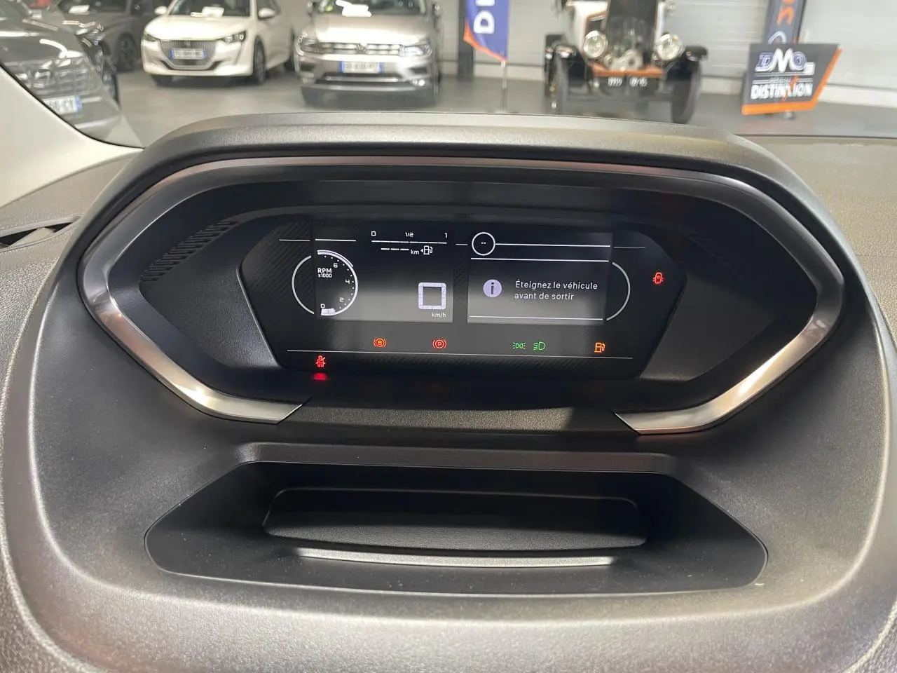 Vue rapprochée du tableau de bord numérique du Peugeot Partner blanc, affichant les alertes et compteurs digitaux.
