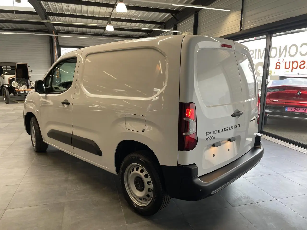 Vue 3/4 arrière droite du Peugeot Partner blanc, fourgon utilitaire avec portes arrière battantes et jantes tôles grises.