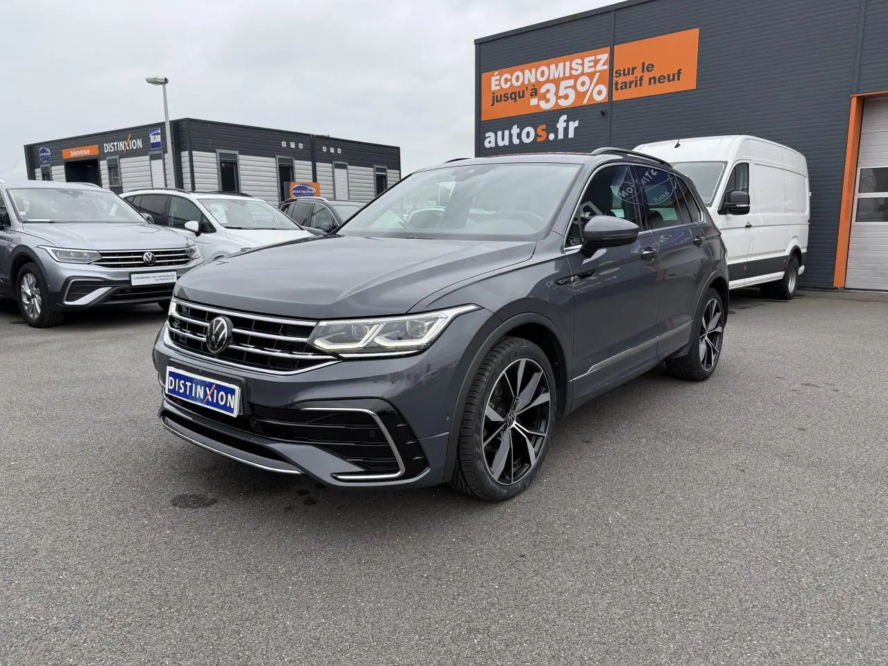 Volkswagen Tiguan gris dauphin en 3/4 avant droit avec jantes alliage noires et calandre chromée visible.