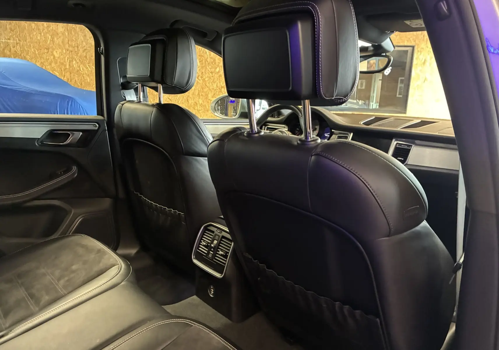 Intérieur arrière noir cuir du Porsche Macan 3.0 360 GTS, vue depuis le côté gauche avec sièges et console centrale visibles.