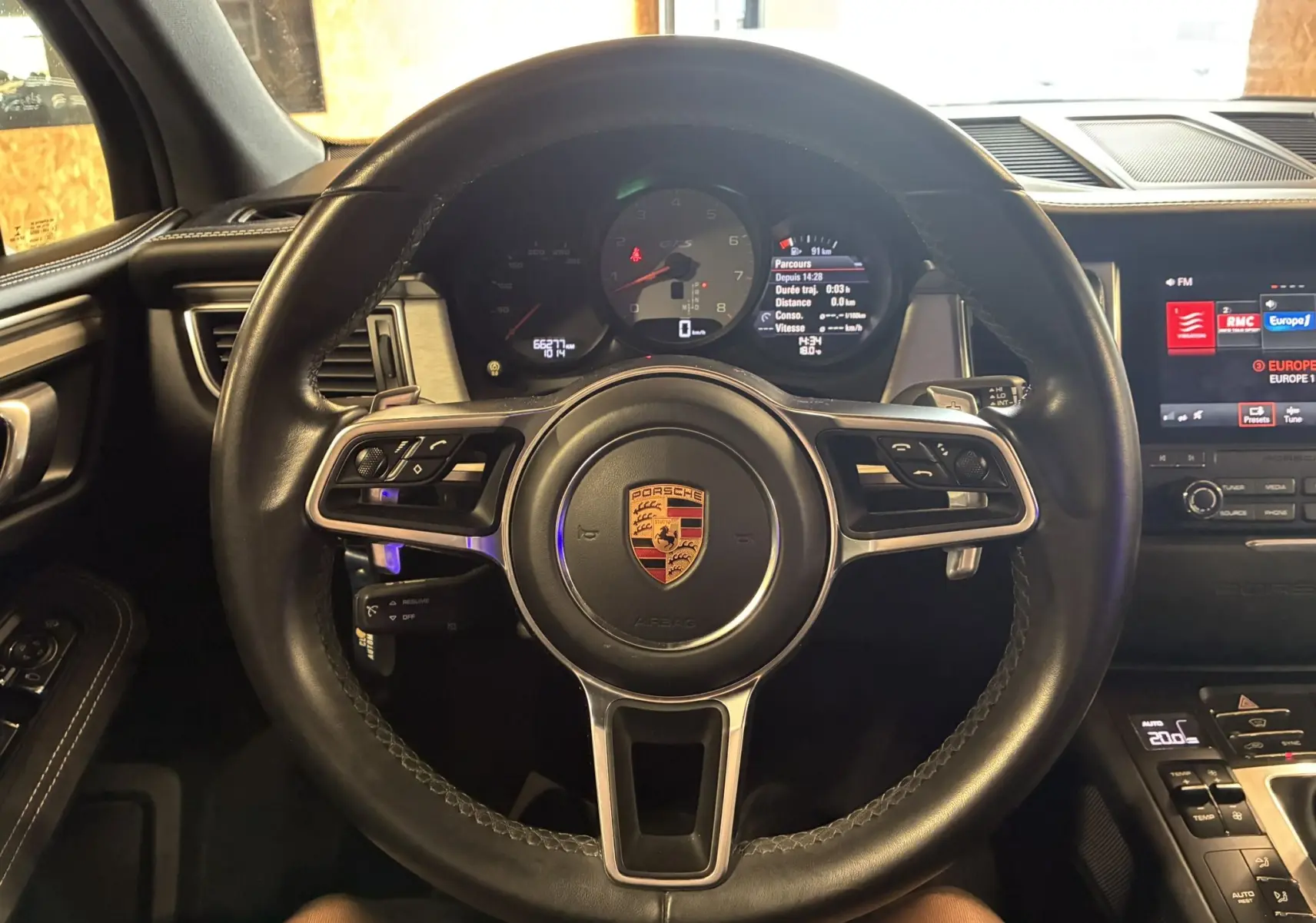 Vue intérieure centrée sur le volant noir en cuir du Porsche Macan GTS 2017 avec tableau de bord numérique et écran tactile.