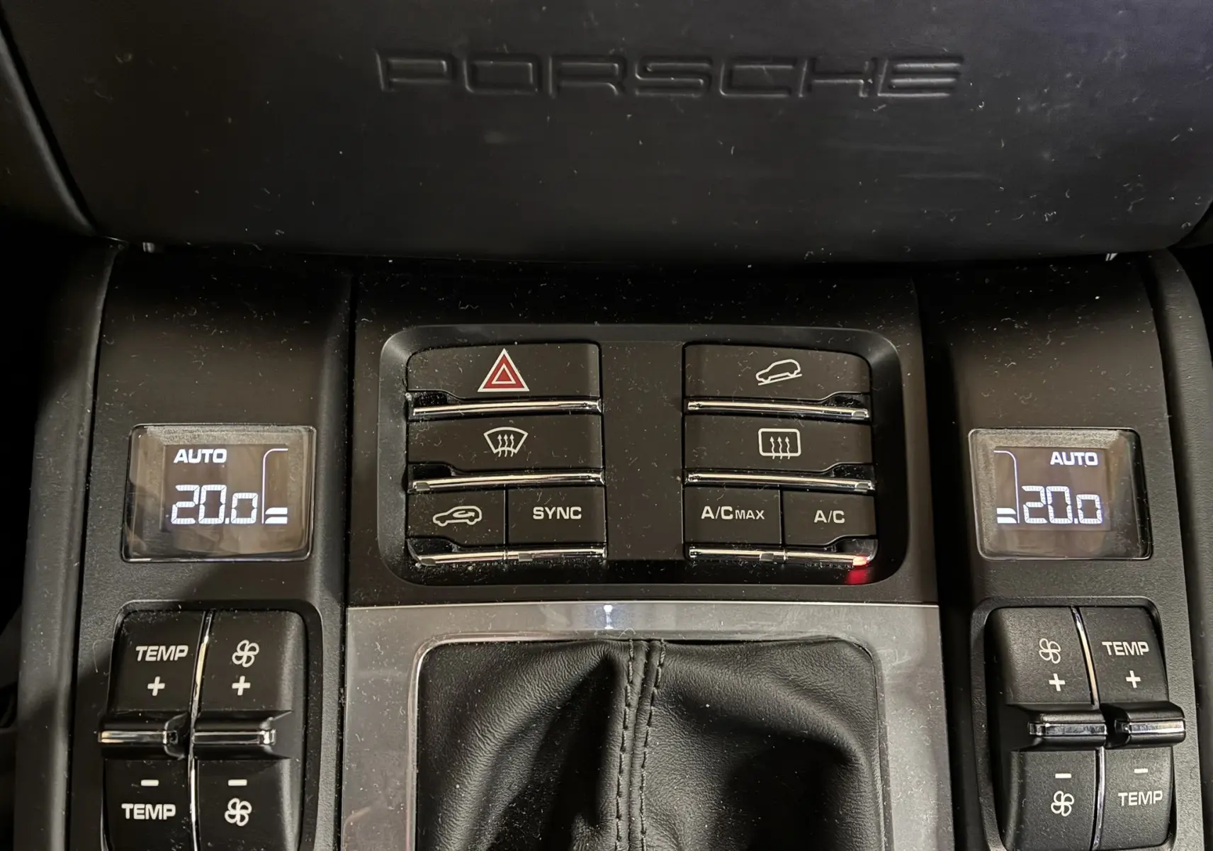 Console centrale noire du Porsche Macan GTS 2017 avec commandes climatisation affichant 20°C et logo Porsche en haut.