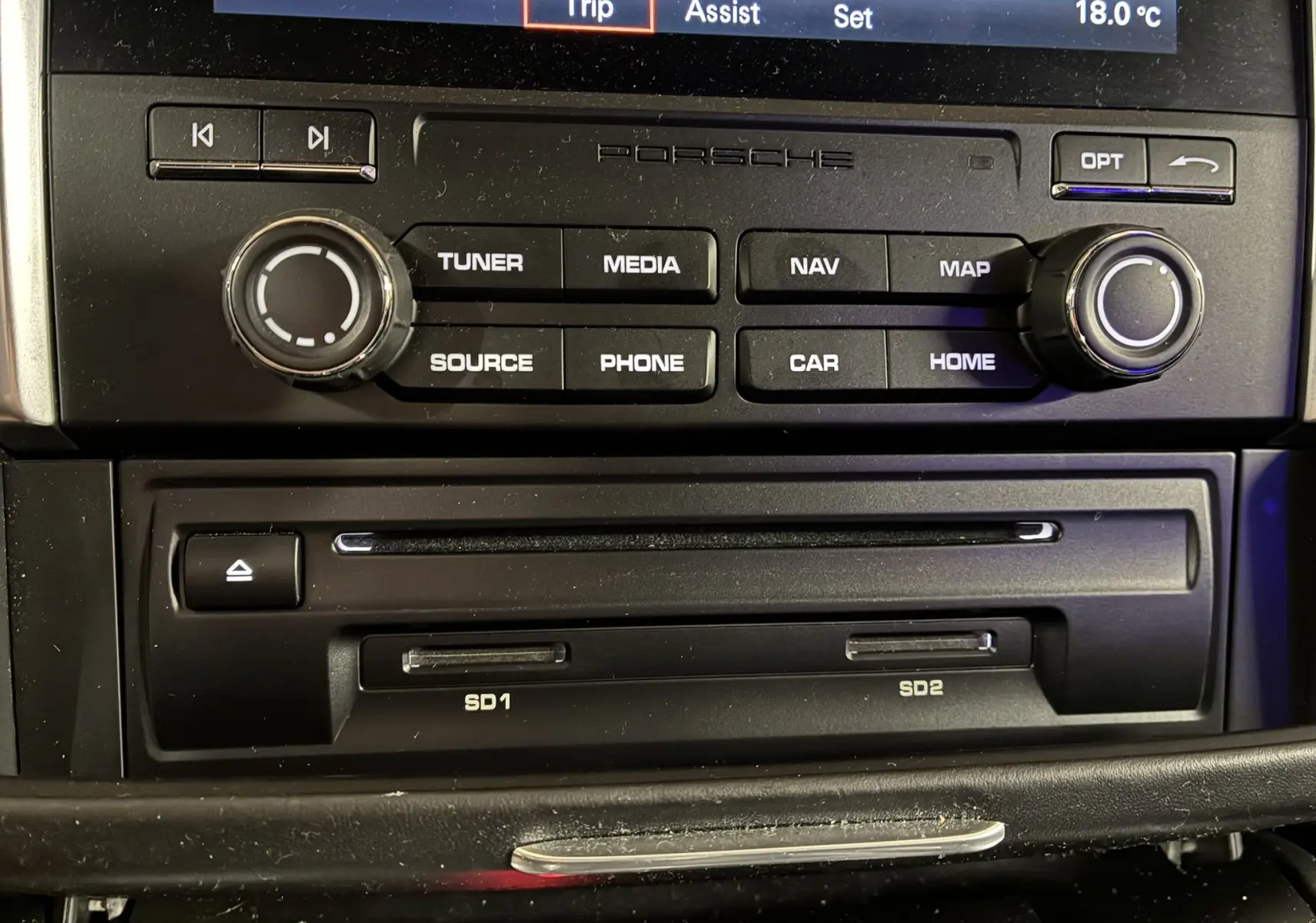 Vue rapprochée de la console centrale noire du Porsche Macan 3.0 360 GTS avec commandes multimédia et lecteurs SD intégrés.