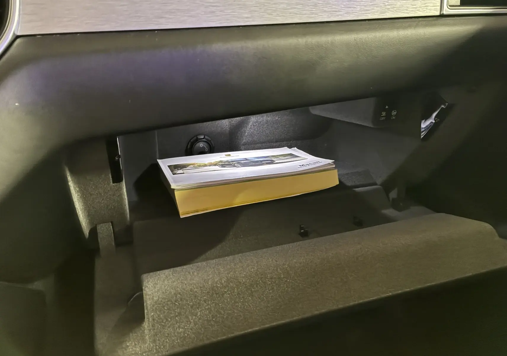 Gant de boîte à gants ouvert avec manuel posé à l'intérieur sur un Porsche Macan GTS 2017 noir.