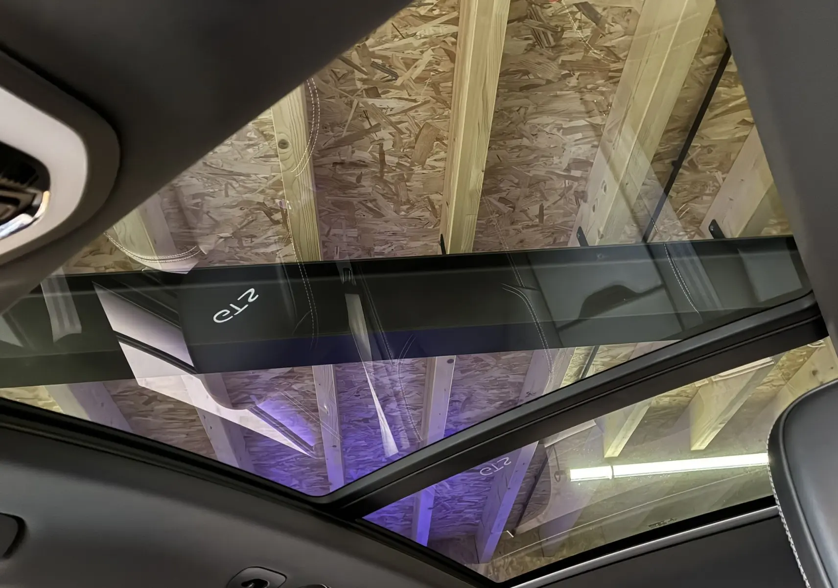 Toit panoramique en verre vu de l'intérieur d'une Porsche Macan 3.0 360 GTS avec ciel de toit noir et surpiqûres blanches