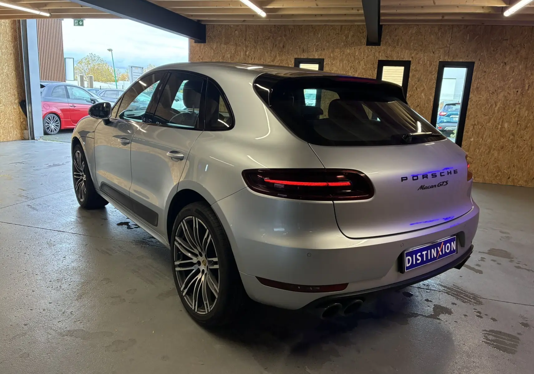 Vue 3/4 arrière droite d'une Porsche Macan GTS 2017 argent avec jantes RS Spyder 20 pouces en intérieur garage.