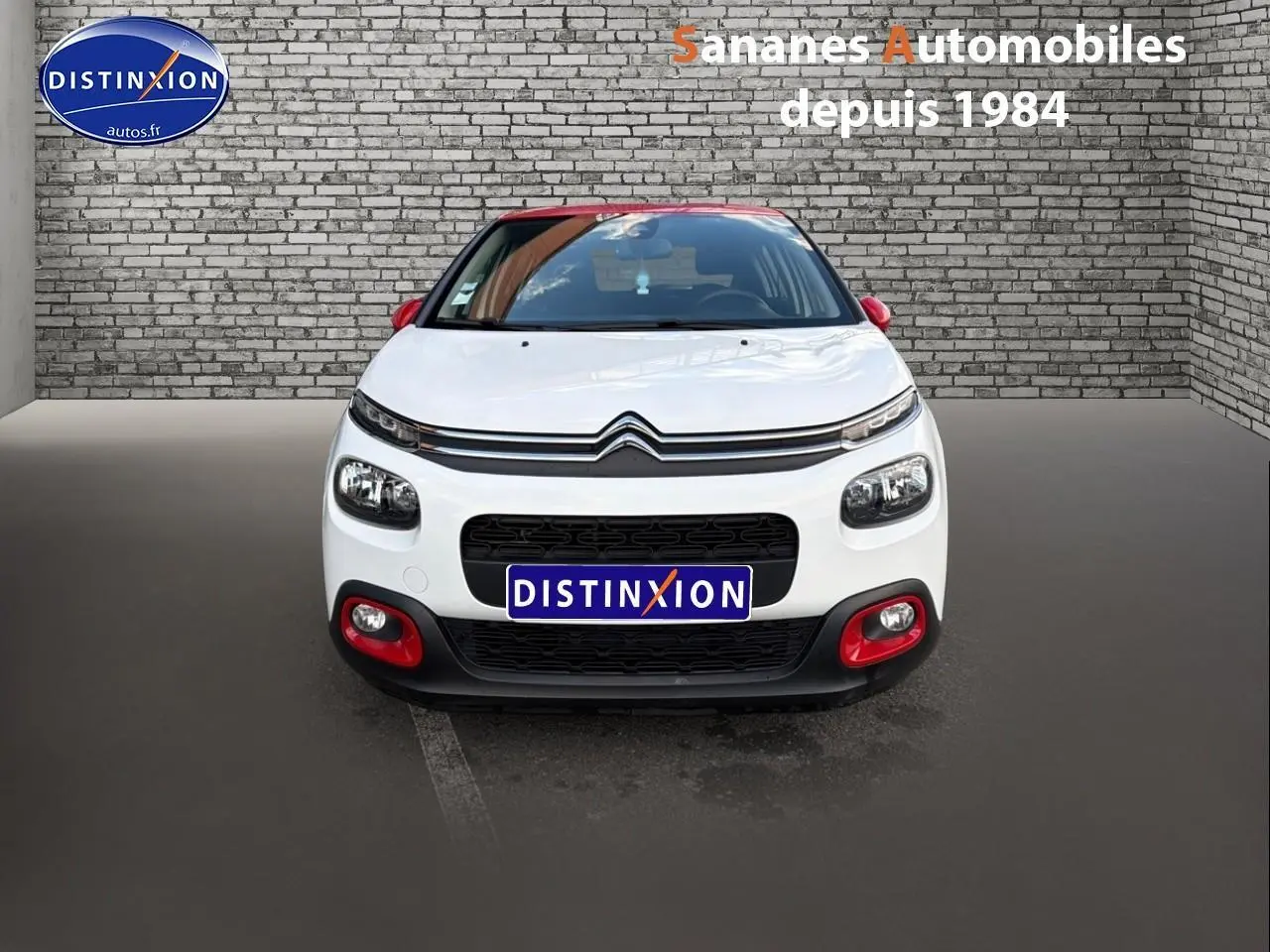 Vue avant d'une Citroën C3 blanche avec toit et rétroviseurs rouges, détails rouges sur le pare-chocs.