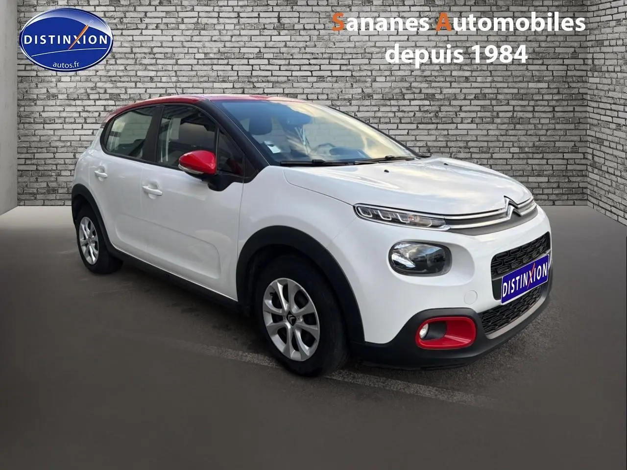 Citroën C3 blanche vue 3/4 avant droit avec toit noir et coques de rétroviseurs rouges.