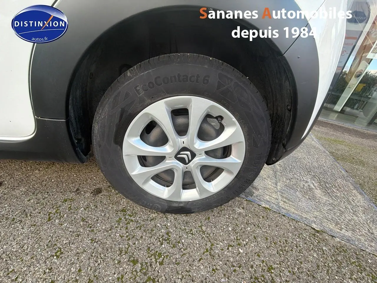 Gros plan sur la roue avant gauche d'une Citroën C3 blanche avec jante en alliage et passage de roue noir.