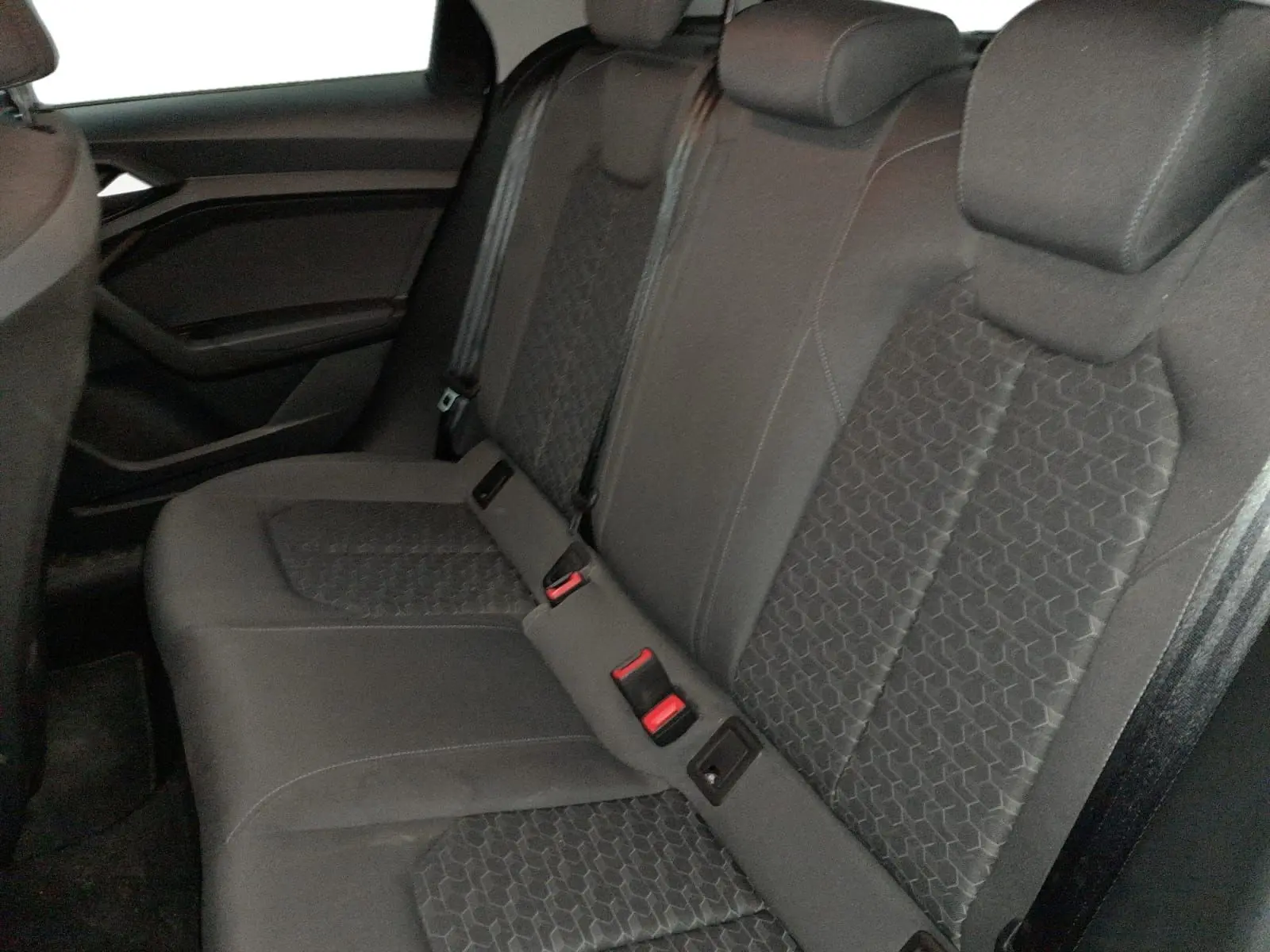 Vue latérale gauche de la banquette arrière noire de l'Audi A1 Sportback 2023 avec sièges sport et ceintures visibles.