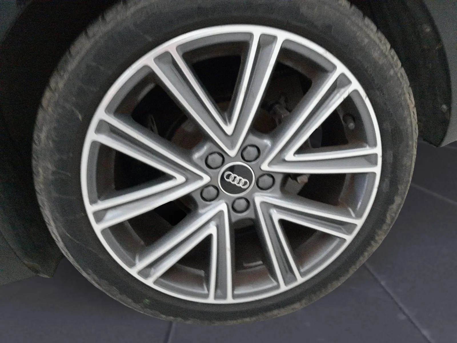 Gros plan sur la jante alliage argentée à design étoilé de l'Audi A1 Sportback noire, roue avant droite.