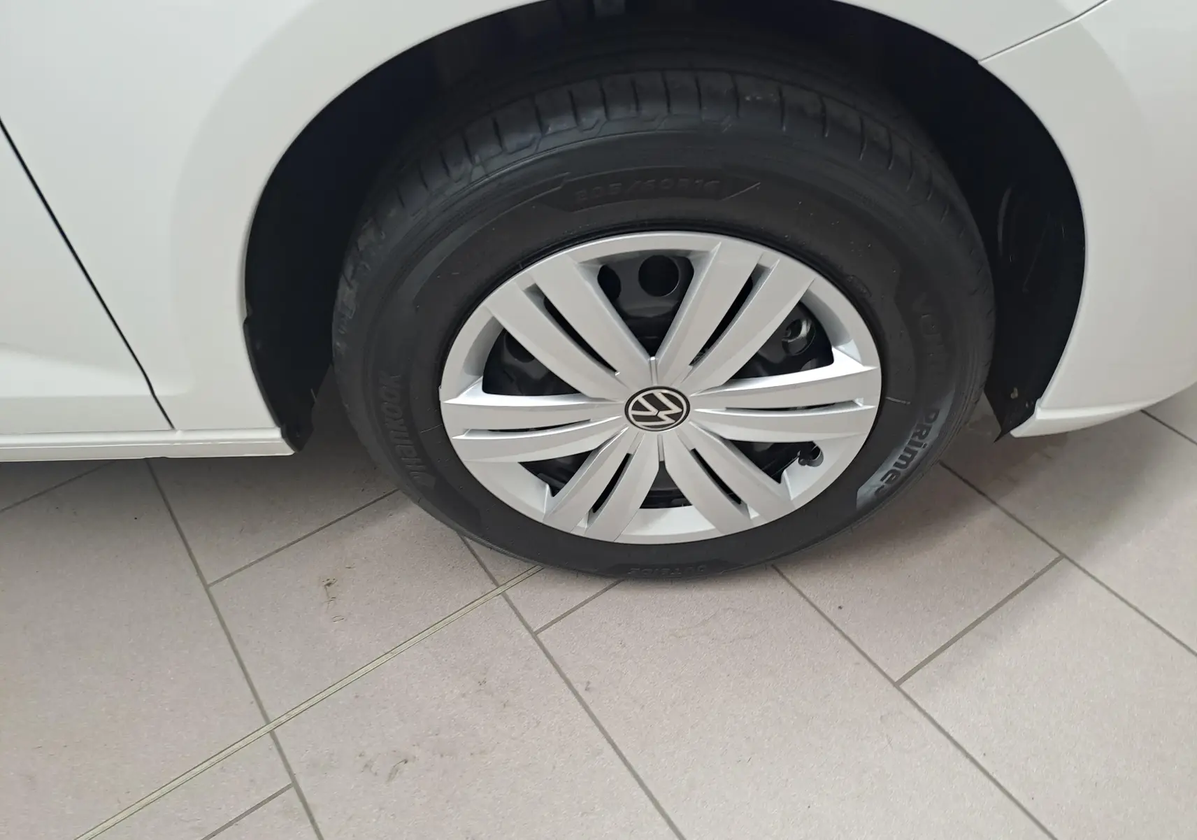 Gros plan sur la roue avant gauche blanche du Volkswagen Caddy Cargo Maxi 2026 avec enjoliveur et pneu Hankook.