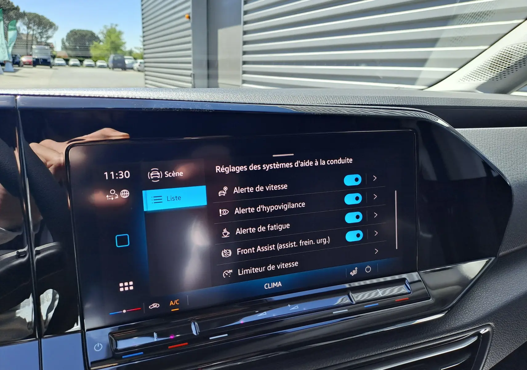 Vue rapprochée de l'écran tactile intérieur du Volkswagen Caddy Cargo Maxi blanc, affichant les réglages d'aide à la conduite.