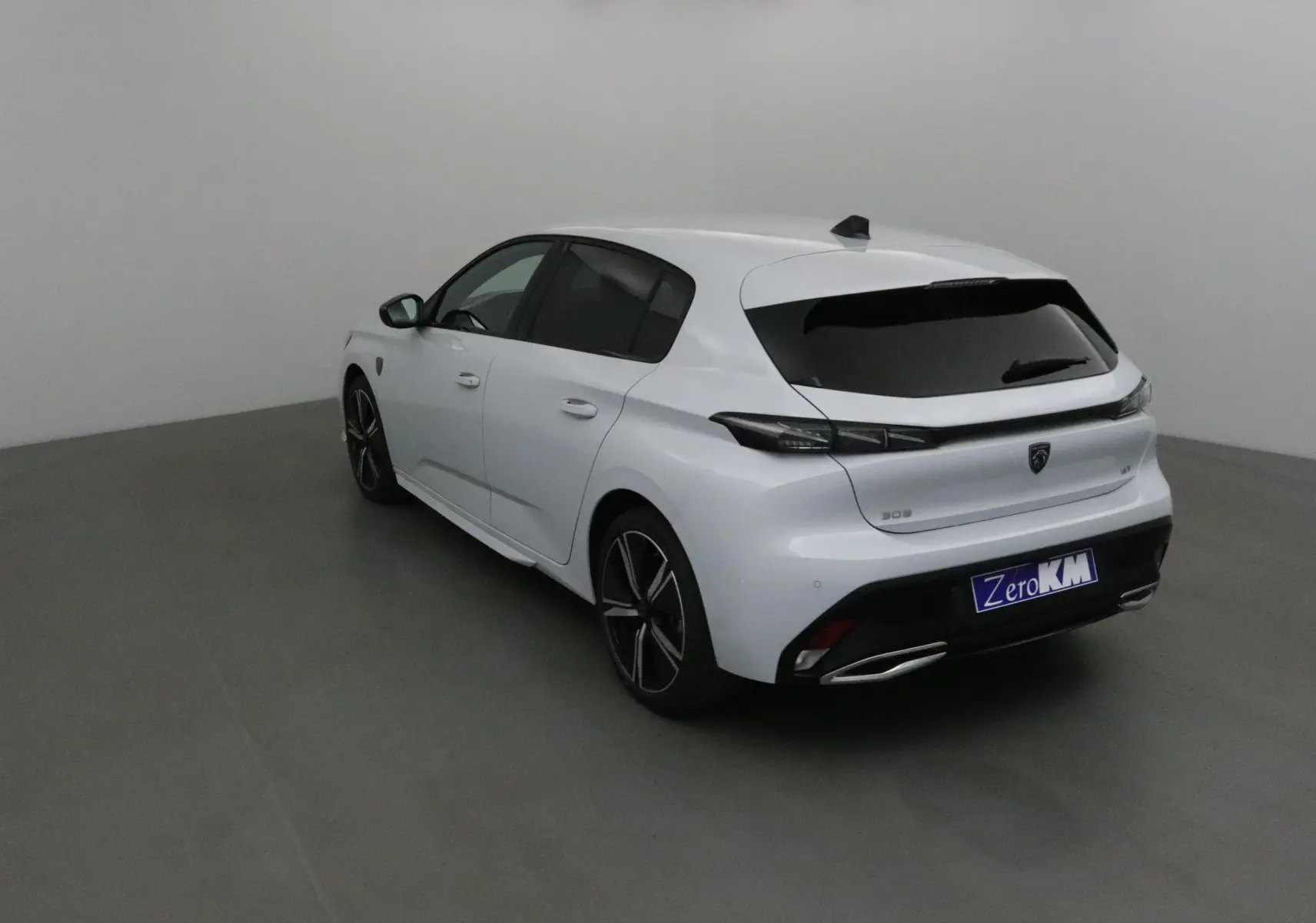 Peugeot 308 blanc Okenite vue 3/4 arrière droit, avec vitres teintées et jantes alliage noires.