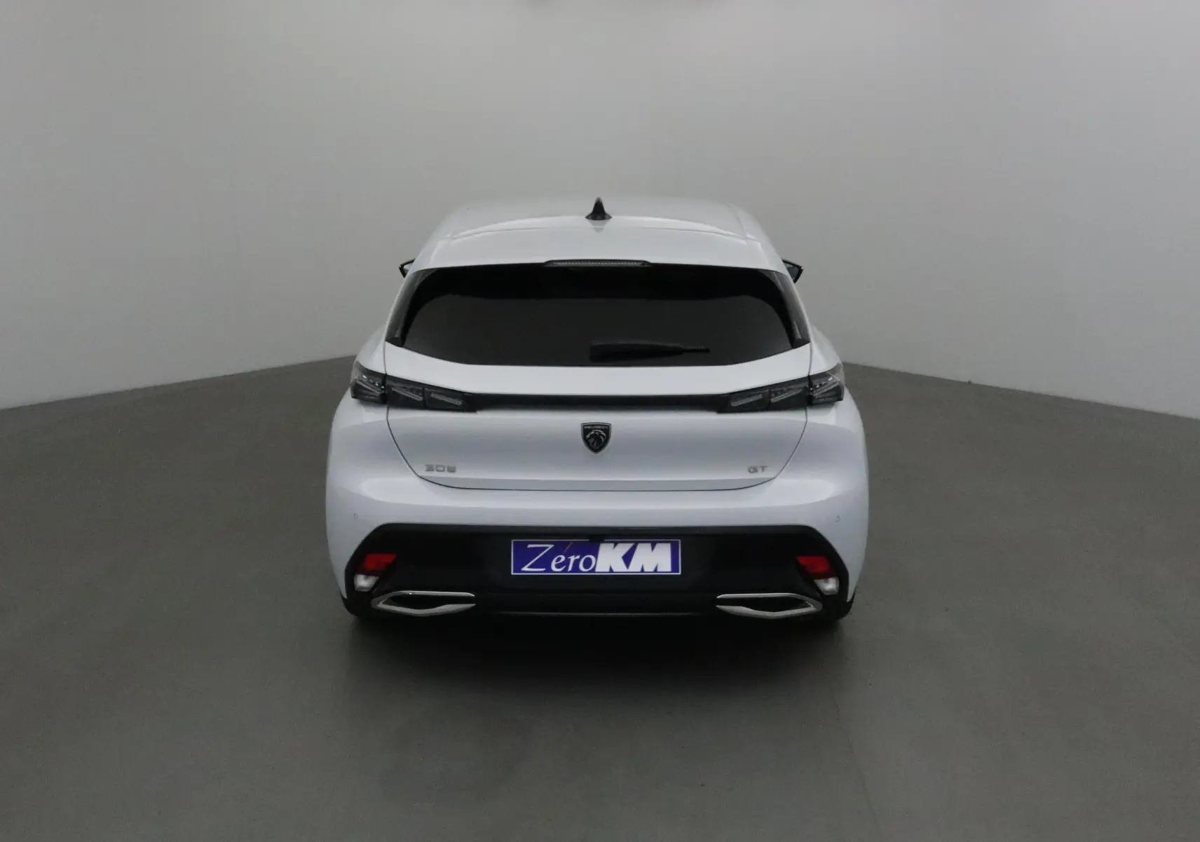 Vue arrière d'une Peugeot 308 GT blanche Okenite avec feux LED et double sortie d'échappement chromée.