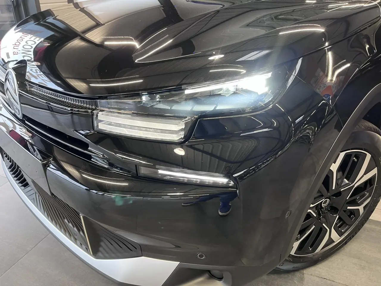 Gros plan sur l'avant droit noir métallisé du Citroën C4 2025 avec phares LED et jante alliage 18 pouces.