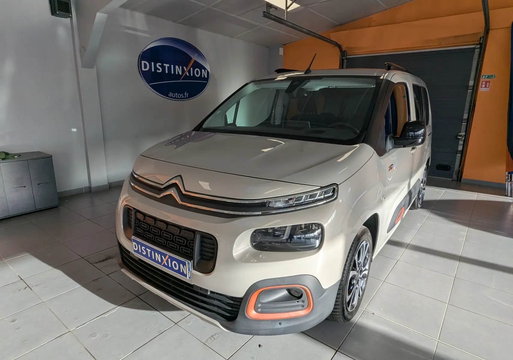 Vue 3/4 avant droite d'un Citroën Berlingo beige 2019 avec détails orange sur pare-chocs et jantes biton.