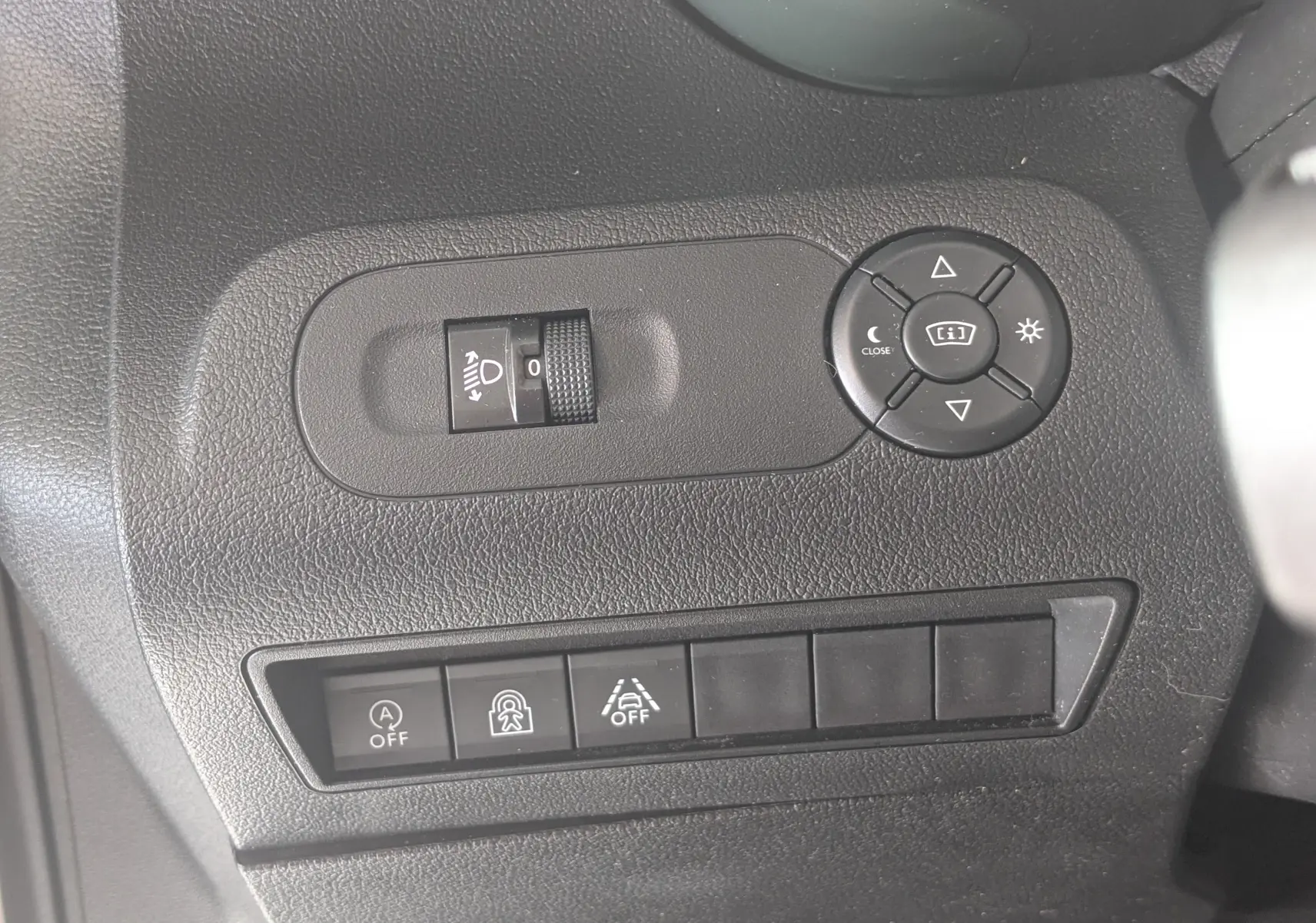 Détail des commandes de réglage des rétroviseurs et des aides à la conduite sur tableau de bord noir du Citroën Berlingo beige.