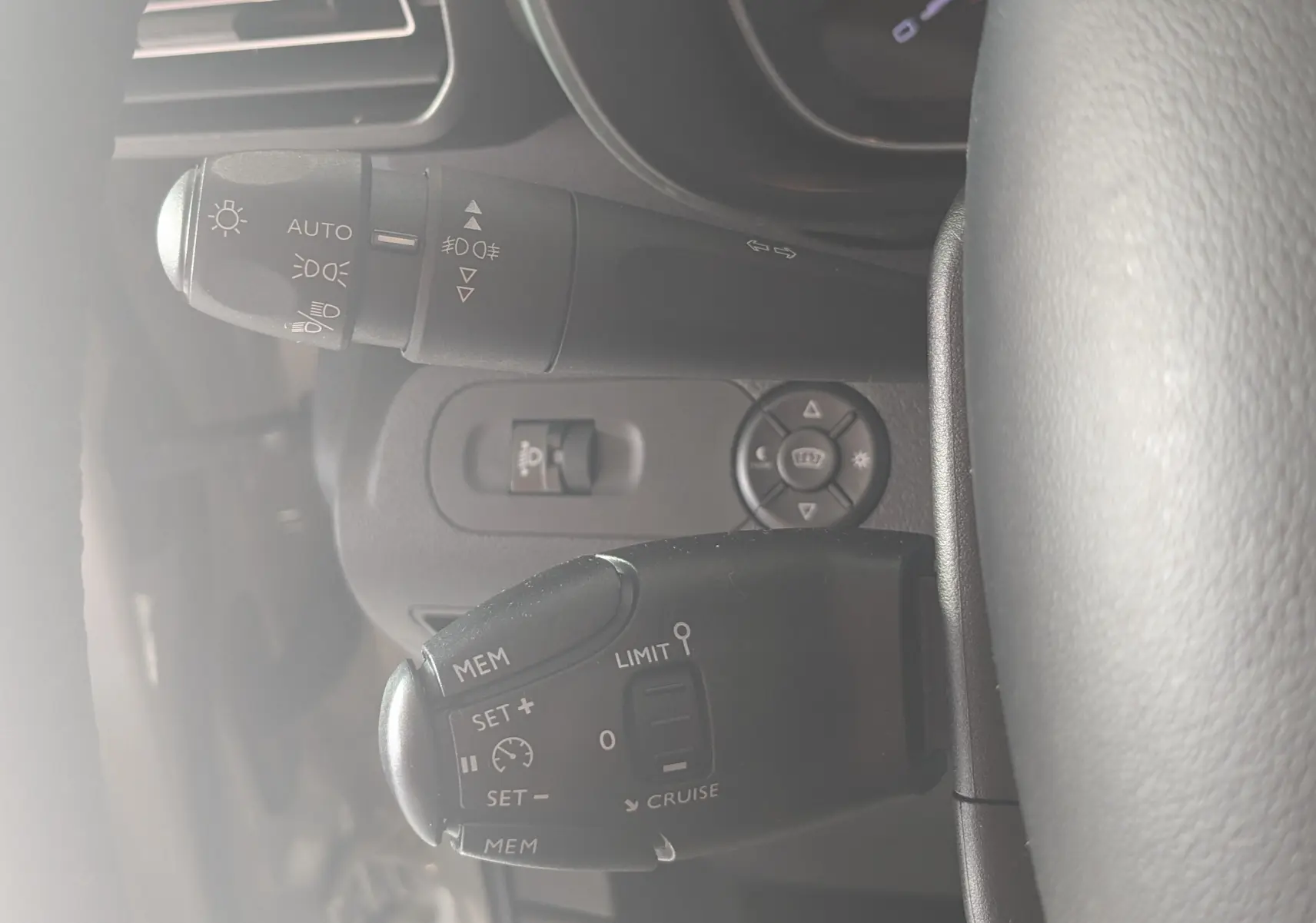 Gros plan sur les commandes au volant du Citroën Berlingo beige 2019, mettant en valeur les boutons de régulateur de vitesse et d'éclairage.