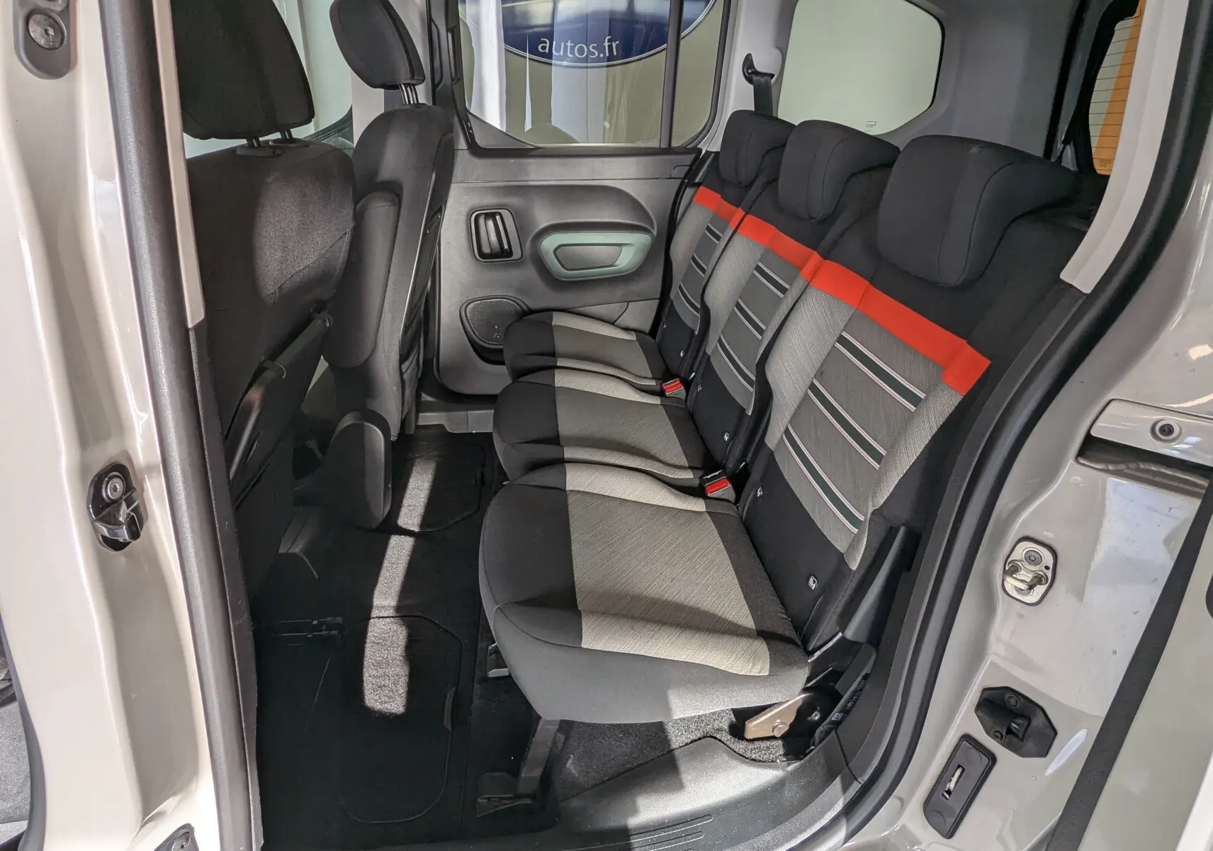 Vue intérieure côté droit des sièges arrière du Citroën Berlingo beige, avec tissu gris et bande orange distinctive.