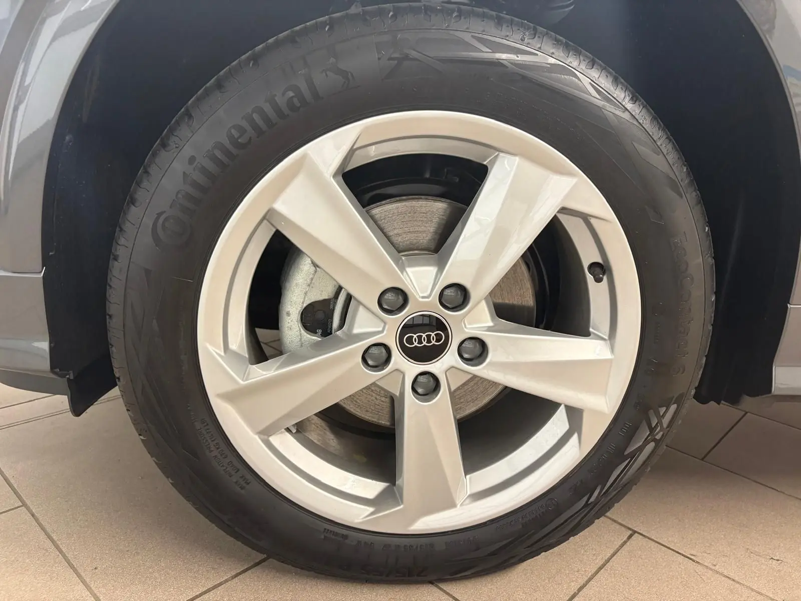 Gros plan sur la roue avant droite de l'Audi Q2 35 TFSI S Line gris Daytona avec jante alliage cinq branches.