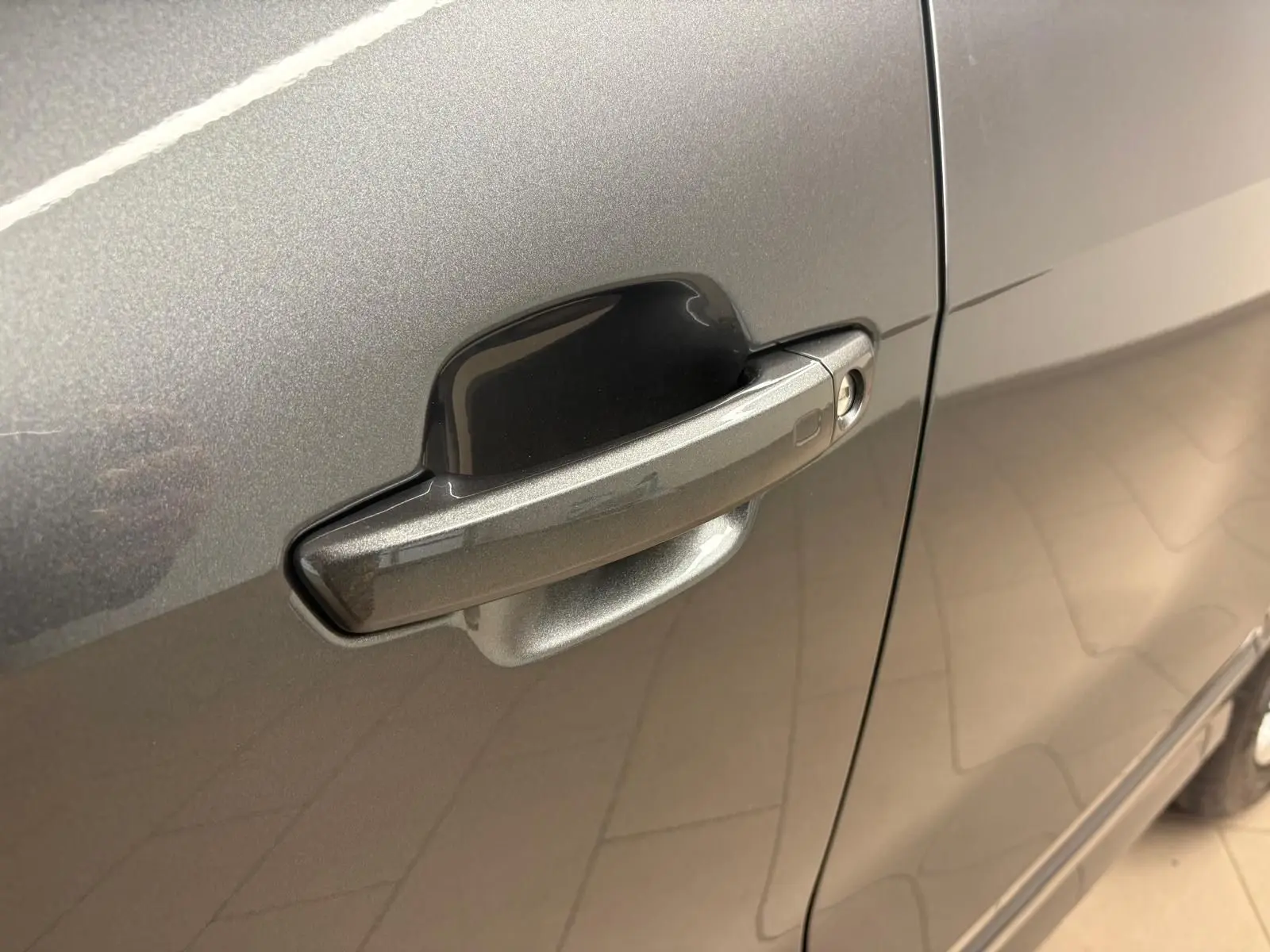 Gros plan sur la poignée de porte côté gauche de l'Audi Q2 35 TFSI S Line gris Daytona métallisé.