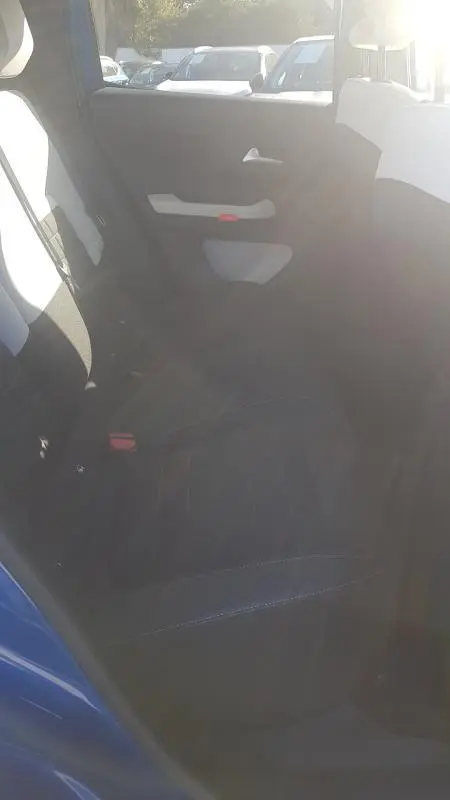 Vue intérieure arrière côté gauche de la Citroën C3 bleu foncé 2024, montrant la banquette et la portière avec accoudoir clair.