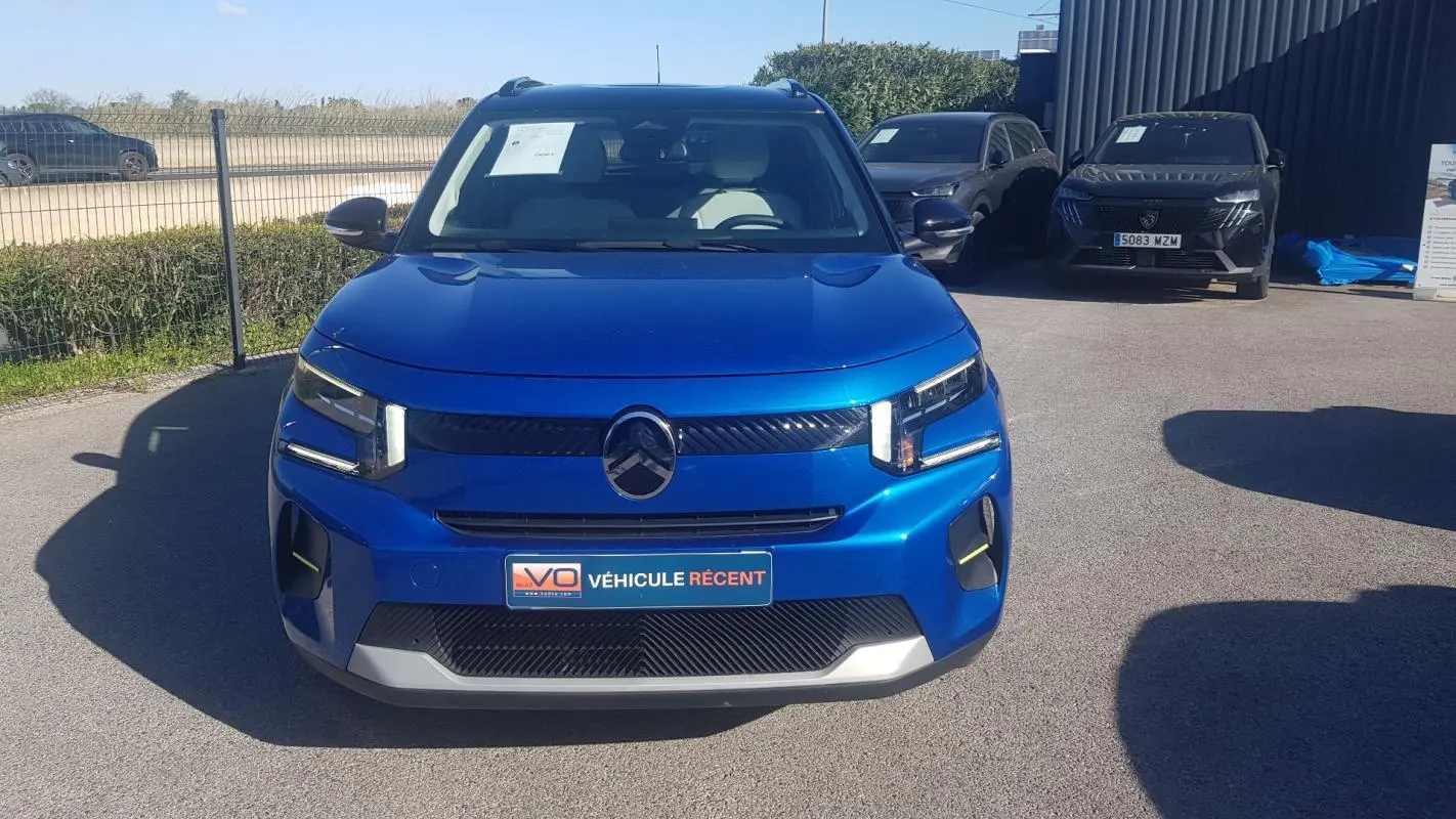 Vue frontale d'une Citroën C3 bleu foncé 2024 avec barres de toit et calandre noire distinctive.