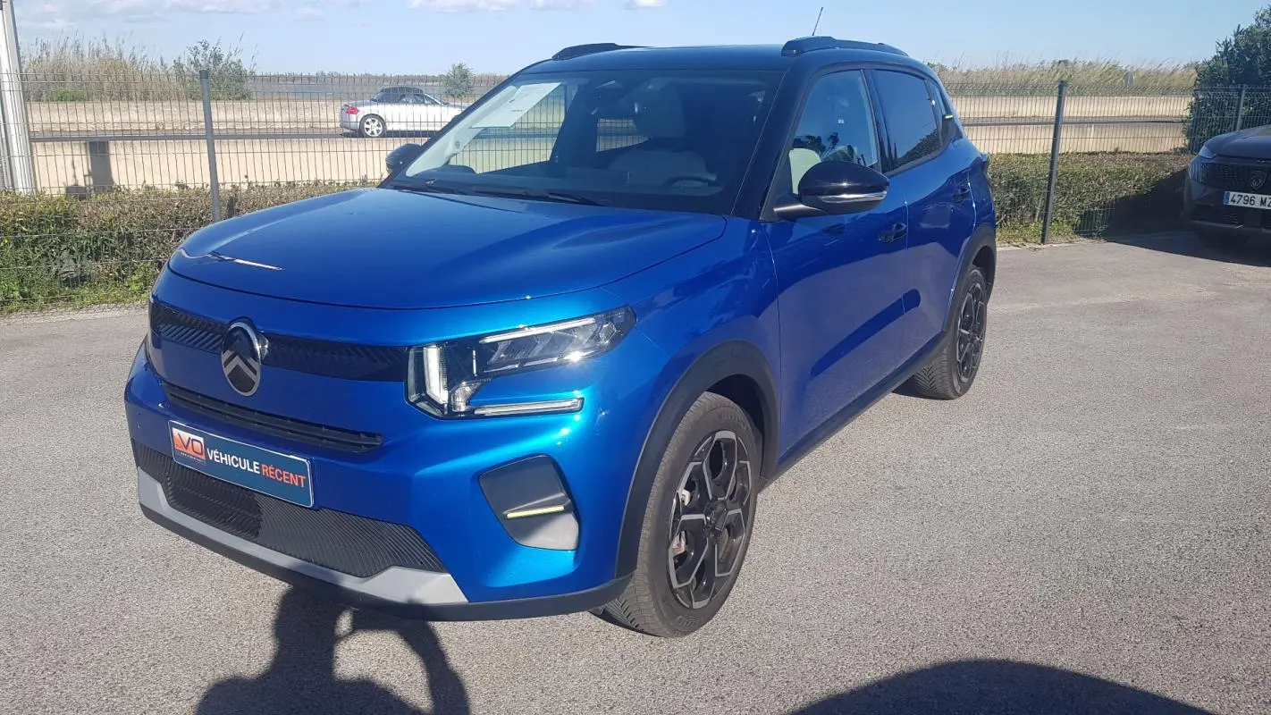 Citroën C3 bleu foncé vue 3/4 avant droit avec barres de toit et jantes alliage noires.