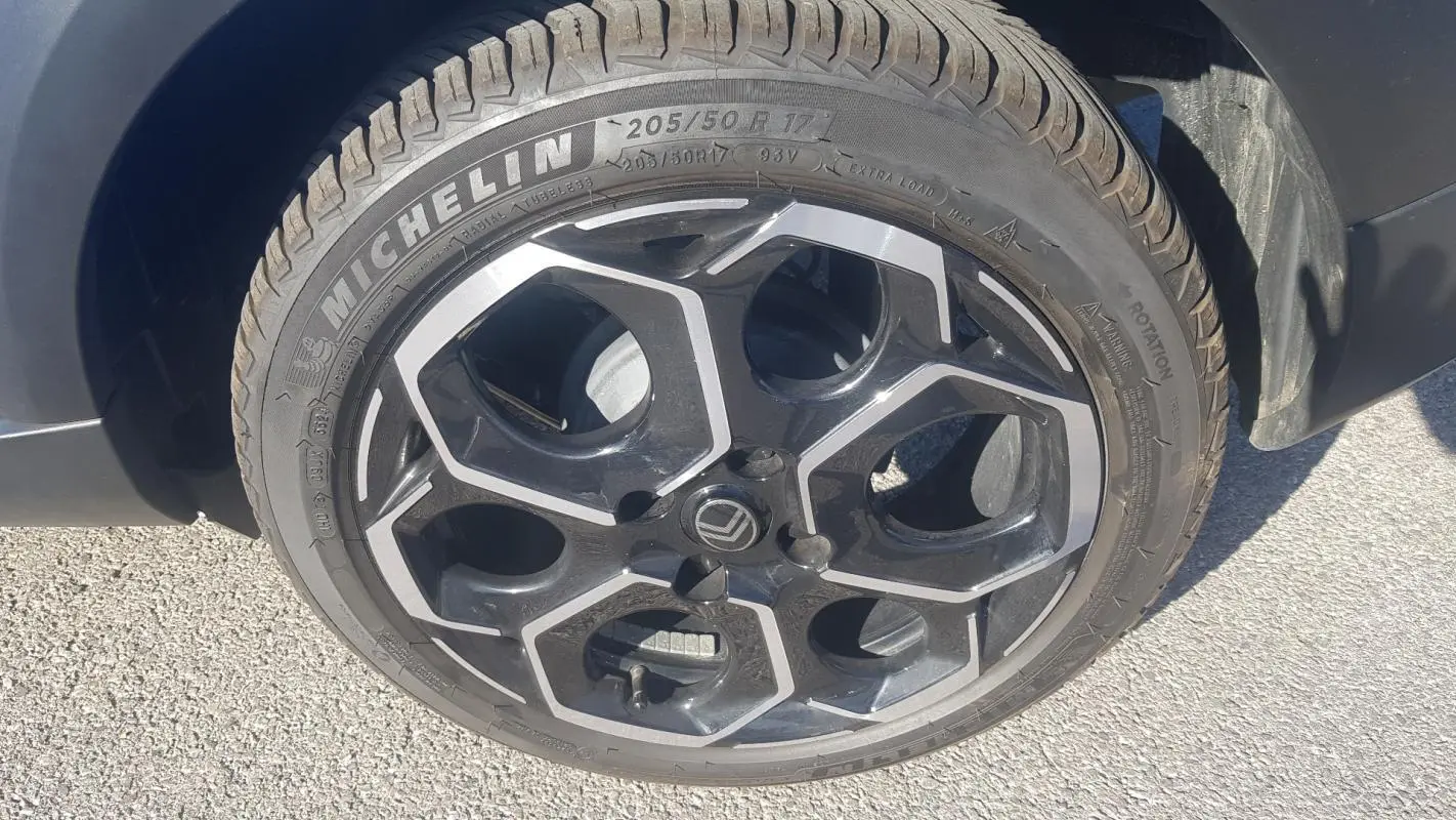 Gros plan sur la jante alliage 17 pouces noire et argentée d'une Citroën C3 bleu foncé, avec pneu Michelin visible.