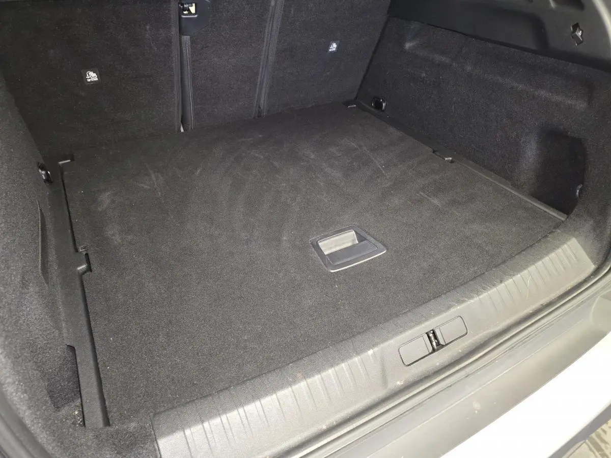 Coffre spacieux et propre du Peugeot 3008 gris, vue intérieure arrière avec plancher plat et poignée centrale.